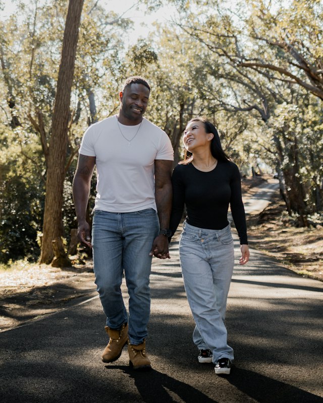 A man in a plain white t-shirt and jeans walking with a woman in a black top and light jeans